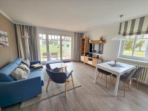 ein Wohnzimmer mit einer blauen Couch und einem Tisch in der Unterkunft Dünenpark Binz - Komfort Ferienwohnung mit 1 Schlafzimmer und Terrasse im Erdgeschoss 115 in Binz