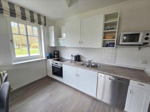 eine Küche mit weißen Schränken und einer Spüle und einem Fenster in der Unterkunft Dünenpark Binz - Komfort Ferienwohnung mit 1 Schlafzimmer und Terrasse im Erdgeschoss 115 in Binz