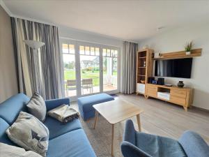 ein Wohnzimmer mit einem blauen Sofa und einem Fernseher in der Unterkunft Dünenpark Binz - Komfort Ferienwohnung mit 1 Schlafzimmer und Terrasse im Erdgeschoss 115 in Binz