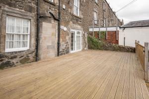 a wooden deck in front of a brick building at Stirling Townhouse Apartment Btm in Stirling
