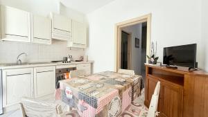 une cuisine avec une table et un évier ainsi qu'une cuisine avec des placards blancs dans l'établissement P062 - Porto Recanati, bilocale a 30mt dal mare, à Porto Recanati