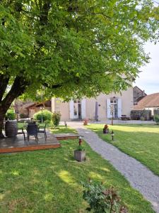 a garden with a table and chairs under a tree at Maison d'Eusébia in Château-Chalon