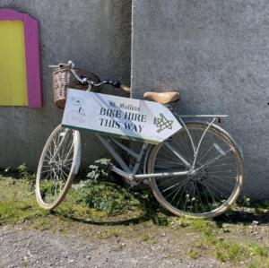 una bicicletta parcheggiata accanto a un muro con un cartello sopra di Mullichain Glamping a Saint Mullins