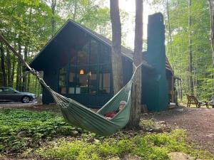 a person in a hammock in front of a house at Cozy Cottage 1 Block Walk From Lake Naomi - Poconos Pennsylvania Area 2 hours from New York City or Philadelphia - Pets Welcome - Check Minimum Night Requirement in Pocono Pines