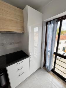 a kitchen with white cabinets and a large window at Apartman Foz Lagoon in Foz do Arelho
