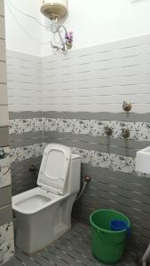 a bathroom with a toilet and a green bucket at Maa Bhagwati Home stay & PG House in Ayodhya
