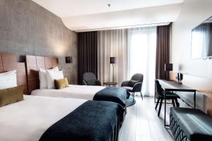 a hotel room with two beds and a desk at Scandic Simonkenttä in Helsinki