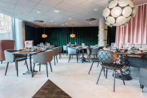 a dining room with tables and chairs and a chandelier at Scandic Simonkenttä in Helsinki