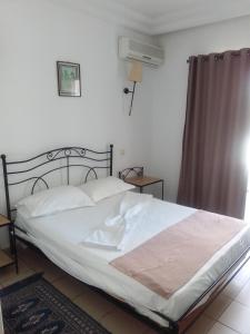 a bedroom with a bed with white sheets and a window at Hotel Les Citronniers Hammamet in Hammamet +9 photos