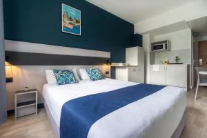a bedroom with a large bed with a blue wall at City Résidence Strasbourg Centre in Strasbourg