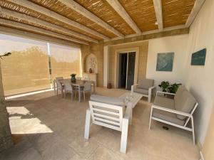 een patio met een tafel en stoelen en een eetkamer bij Villa Malepè con piscina in Torre dell'Orso +59 foto's