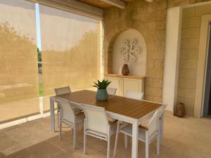 een houten tafel en stoelen in een kamer met een raam bij Villa Malepè con piscina in Torre dell'Orso