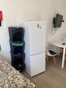 Un refrigerador blanco con cuatro contenedores al lado de una mesa. en Vila Alegre, en Fuseta