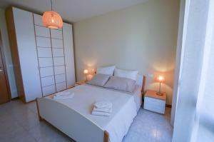 a bedroom with a large white bed and two lamps at Casa Origine, appartamento vista piscina, al mare in Cavallino-Treporti +13 photos