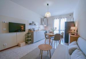 a living room with a couch and a kitchen with a table at Casa Origine, appartamento vista piscina, al mare in Cavallino-Treporti