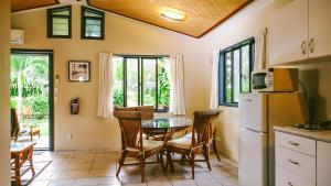 a kitchen and dining room with a table and a refrigerator at Muri Beach Resort in Rarotonga
