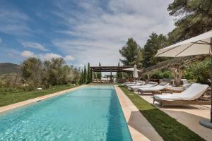 an outdoor swimming pool with lounge chairs and an umbrella at Can Ribes Ibiza in Illes Balears