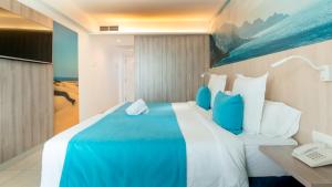 a bedroom with a large bed with blue and white pillows at Labranda Marieta & Spa - Adults Only in Playa del Ingles