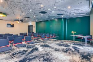 a room with chairs and tables and a green wall at ibis Bucharest Politehnica in Bucharest