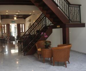 a lobby with a staircase with wicker chairs and a table at Heeren Straits Hotel in Malacca