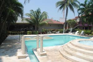 a swimming pool with palm trees and a building at Los Andes Coatzacoalcos in Coatzacoalcos