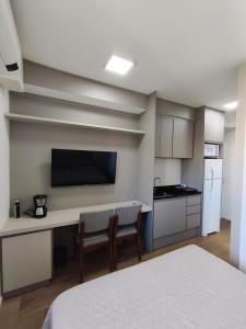 a room with a kitchen with a desk and a tv at Studio SUPER LUXO a 5 min do Nubank Parque in São Paulo