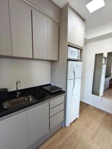 a kitchen with white cabinets and a white refrigerator at Studio SUPER LUXO a 5 min do Nubank Parque in São Paulo