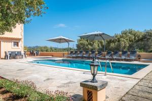 a swimming pool with chairs and umbrellas at Can Jeroni Petit in Cala Ferrera