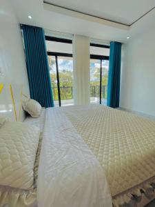 a large bed in a bedroom with windows at Iwabo Apartments Kigali Airport Kanombe in Kigali