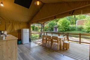 Tienda de campaña con mesa y sillas en una terraza en Tente Lodge 8 personnes, en Saint-Martial-de-Nabirat