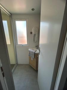 Un baño con lavabo y ventana. en Mobilhome sur camping 4 étoiles, en Le Teich