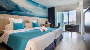 a hotel room with a large bed with a blue blanket at Labranda Marieta & Spa - Adults Only in Playa del Ingles