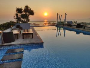 a swimming pool with a sunset in the background at The Gallery Condominium B in Jomtien Beach