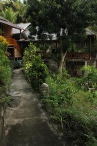 a path in front of a house with trees and plants at Malenge Dive Resort in Pulau Malenge