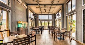 a restaurant with tables and chairs and windows at Break the Routine, Malshej in Murbād