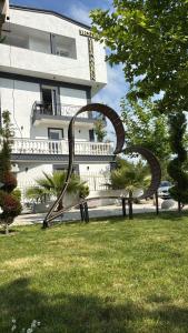 um banco de parque na relva em frente a um edifício em Hotel Vila AARON em Durrës