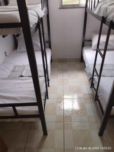 a dorm room with bunk beds and a tile floor at Casa Pedra in Pedra de Guaratiba