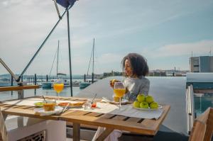 eine Frau, die mit Weingläsern an einem Tisch auf einem Boot sitzt in der Unterkunft Exclusivas vistas al mar en casa barco, pleno centro, terraza, parking in A Coruña