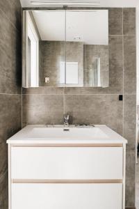 a bathroom with a white sink and a mirror at DINBNB Apartments l 100m to Bryggen l Pet Friendly l Sleeps 4 l Smart-TV in Bergen