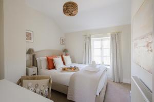 a white bedroom with a bed and a window at Tilly's Cottage in Bourton on the Water