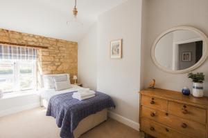 ein Schlafzimmer mit einem Bett, einem Spiegel und einer Kommode in der Unterkunft Tilly's Cottage in Bourton on the Water + 27 Fotos