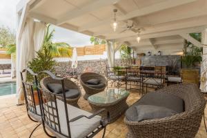 an outdoor patio with wicker chairs and a table at Le Grand Badamier Blanc grande villa familiale 5 étoiles piscine chauffée 17 personnes in Saint-Paul