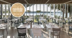 a restaurant with white tables and chairs and windows at Falkensteiner Hotel Park Punat in Punat
