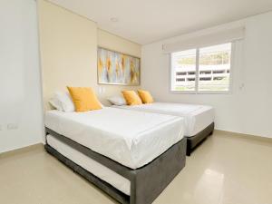 two beds in a bedroom with white walls and a window at Apartamentos con vista al mar Brisa Marina Rodadero - by Bedviajes in Santa Marta