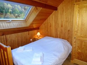 Una cama en una habitación de madera con ventana. en Les Oulles 17, en La Chapelle-en-Valgodemard
