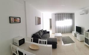 Una sala de estar con un sofá y un televisor. en Residencial Amber II - Apartamento nuevo, amplio y cómodo, en Vecindario