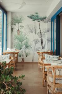 ein Esszimmer mit Tischen und einem Wandbild mit Palmen in der Unterkunft Hotel Honucai in Colonia Sant Jordi