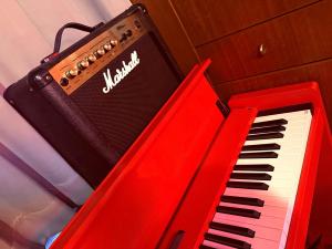 a red piano sitting next to a black and white keyboard at GRAND HOTEL SHISA St OKINAWA グランドホテル シーサーストリート沖縄 in Urasoe