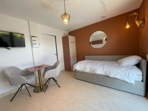 une chambre avec un lit, une table et un miroir dans l'établissement Les gites du champ des oiseaux, à Saint-Amand-les-Eaux