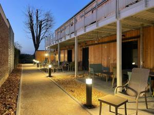 un patio avec des chaises et des tables sur un bâtiment dans l'établissement Les gites du champ des oiseaux, à Saint-Amand-les-Eaux